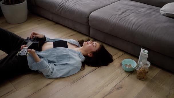 年轻女子躺在沙发旁边的地板上玩羽毛球 — 图库视频影像