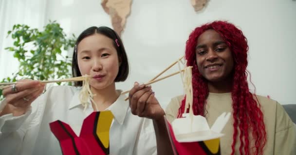 箸で家で一緒に麺を食べる多様な女性の友人 肯定的な気分 — ストック動画