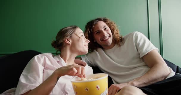 愛するカップル見る映画で一緒にリビングルームにホーム 女性供給とともにポップコーン彼のボーイフレンド — ストック動画