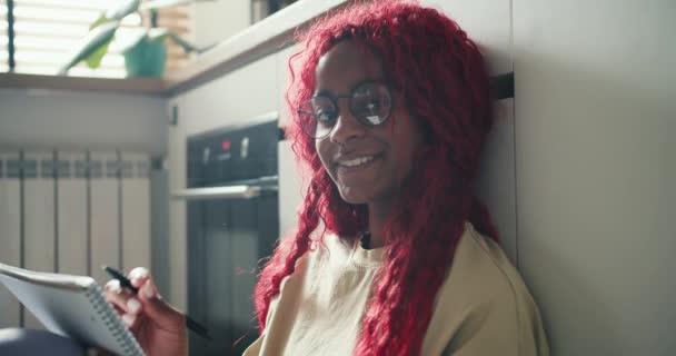 Afroamerikanisches Mädchen Mit Roten Lockigen Haaren Studiert Auf Dem Küchenboden — Stockvideo