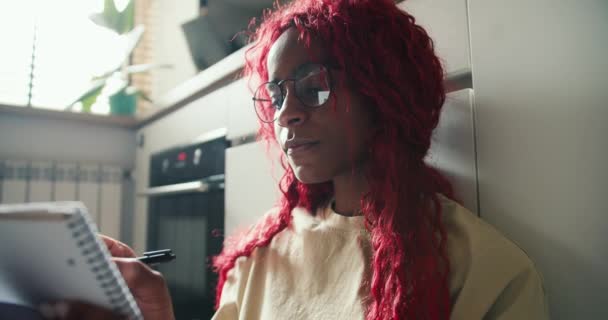 Afroamerikanisches Mädchen Mit Rotgelockten Haaren Studiert Auf Dem Küchenboden Und — Stockvideo