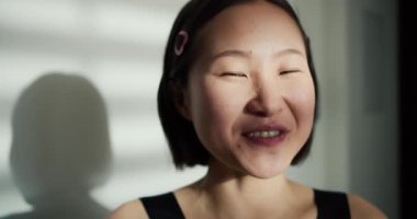 Asyalı kadın kameraya bakıyor çevrimiçi bir video görüşmesi yapıyor gülümseyen yüzle konuşuyor bir arkadaşla iletişim kuruyor, poz veriyor..