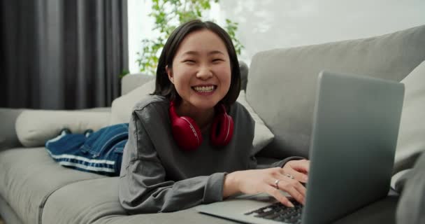 Portrait Asian Woman Typing Laptop While Laying Sofa Looking Camera — Stock Video