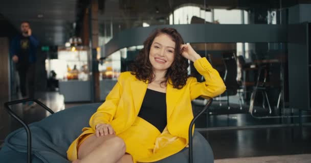 魅力与自信 职业定位的艺术 一个穿着黄色夹克的女孩坐在办公室的扶手椅上摆姿势 — 图库视频影像