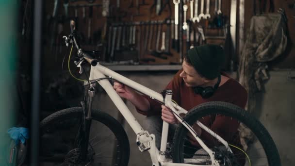 Zvládnutí Podrobností Kvalifikovaný Mechanik Brown Sweater Inspecting White Bike Dílně — Stock video