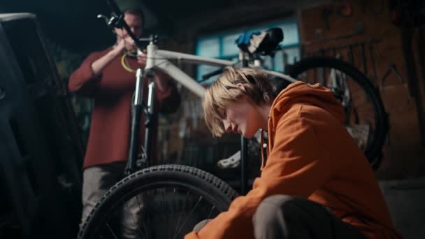 父のフォアマンと彼の息子のアシスタントは ワークショップで自転車修理に取り組んでいます 親子絆 自転車修理の喜び — ストック動画
