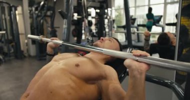 Atletik beyaz adam spor salonunda halter kaldırırken kollarını sallıyor. Profesyonel bir vücut geliştiricinin spor ve ağırlık kaldırması. Sağlıklı ve aktif bir yaşam tarzı..