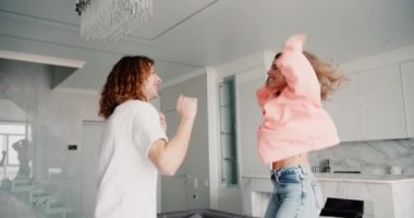 Modern oturma odasında mutlu genç aile dansı, eğlenceli dans hareketleri, kanepede zıplayan kız..