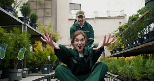 Greenhouse Fun Trabalhadores Transportando Plantas Carrinho Com Joyful Girl Waving — Vídeo de Stock