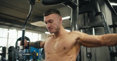 Odaklanmış bir atlet egzersiz makinesinde kol kaslarını esnetir. Spor salonundaki tüm kol kaslarını çalıştırıyorum..