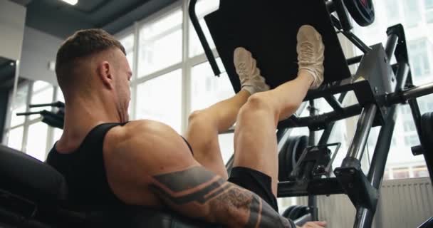 Muscular Man Performs Exercises Sports Training Apparatus Leg Muscles Gym — Stock Video