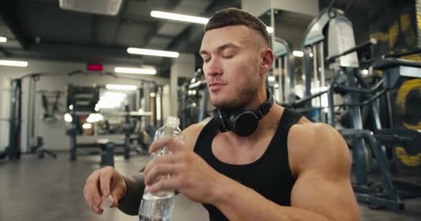 Aktivní Muž Odpovídá Tričkem Sluchátkách Pije Vodu Dalším Cvičení Tělocvičně — Stock video