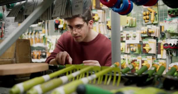 Explorando Equipo Jardinería Una Tienda Especializada Con Hombre Joven Jersey — Vídeos de Stock