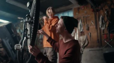 Baba ve oğlu garajda çalışıyor, motorun zinciri çalışıyor mu diye kontrol ediyorlar..