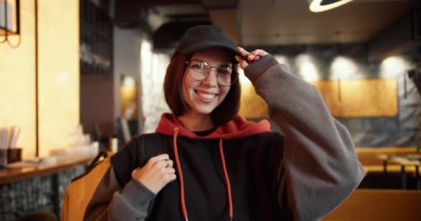 Νεαρή Delivery Γυναίκα Φορώντας Καπέλο Στέκεται Σακίδιο Στο Μοντέρνο Εστιατόριο — Αρχείο Βίντεο