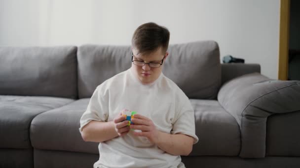 Człowiek Zespołem Downa Siedzi Domu Podłodze Bawi Się Kostką Rubika — Wideo stockowe