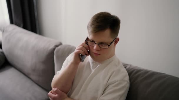 Jovens Downs Síndrome Cara Sentado Sofá Usando Telefone Celular Casa — Vídeo de Stock
