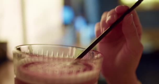 カクテルディライトの魅力 スタイリッシュなバーでピンクの飲み物を楽しむ女の子の高品質のクローズアップ設定 — ストック動画