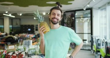 Neşeli Citrus Sunumu: Gülümseyen Esmer Adam Süpermarkette Ananas Pozisyonları.