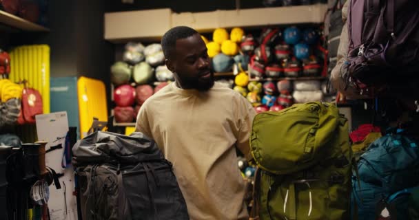 黑人在专门的齿轮商店里选择背包困境 — 图库视频影像