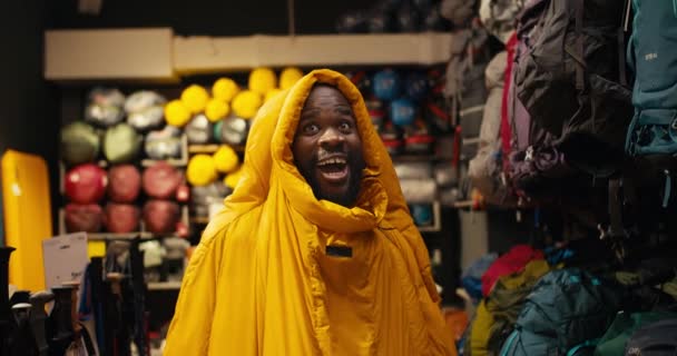 Афроамериканец Магазине Снаряжения Пеших Прогулок Носит Желтый Спальный Мешок Вытягивает — стоковое видео