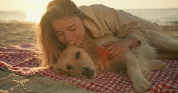 特写镜头 一个金发女孩和她那只可爱的浅色大狗肩并肩躺在一个阳光灿烂的海滩上的垫子上 和你的宠物在一起很开心 — 图库视频影像