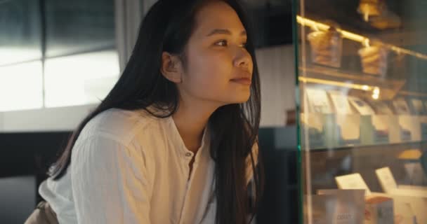 一个身穿白衬衫的年轻的黑发亚洲女孩选择了她的甜点 休息期间在工作中休息和吃零食 — 图库视频影像