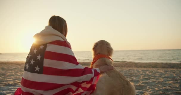 Strzał Bliska Blondynka Siedzi Rano Słonecznej Plaży Psem Zawiniętym Amerykańską — Wideo stockowe
