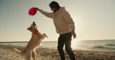 Ve genç bir adam, büyük açık renkli köpeğiyle birlikte, sabah kumsalda oynuyorlar..
