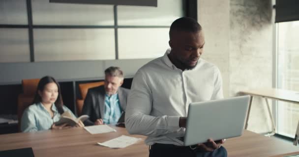 在一个成功的多种族三人的办公室里做富有成效的工作 在办公室同事的背景下 在笔记本电脑上工作的中年黑人 — 图库视频影像