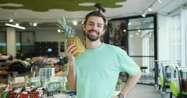 Playful Citrus Prezentace Usmívající Bruneta Mladý Muž Hodí Ananasem Supermarketu — Stock video