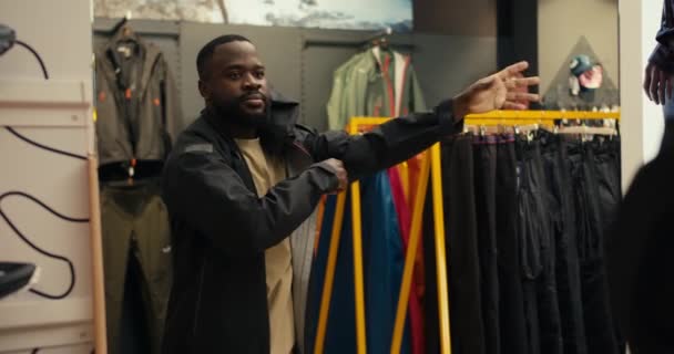 Exploring Style Hombre Afroamericano Probándose Rompevientos Negro Tienda Engranajes Aire — Vídeos de Stock