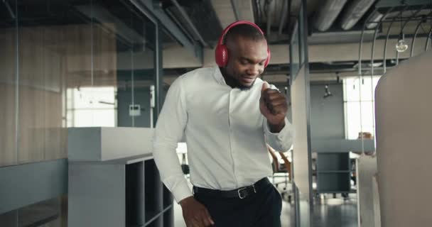 一个中年黑人在办公室里跳舞 一个戴着红色无线耳机的男人在办公室休息的时候 一边听音乐一边跳舞 — 图库视频影像