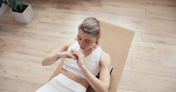 흰옷을 금발의 여자가 양지바른 방에서 실린더를 사용하 강화하기 운동을 들어간다 — 비디오