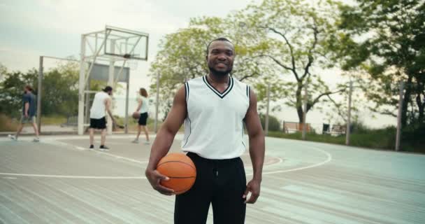 Černoch Basketbalista Basketbalem Ruce Pózuje Dívá Kameru Pozadí Svých Přátel — Stock video