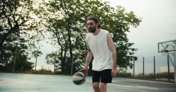 一名身穿白色T恤和黑色短裤的男子在外面的篮球场上熟练地运球 户外运动 — 图库视频影像
