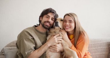 Mutlu bir çiftin portresi: yeşil tişörtlü bir adam ve turuncu kazaklı bir kız poz veriyor ve bir salağın üzerinde bir köpekle birlikte gülümsüyorlar. Mutlu çift ve hayvanları.