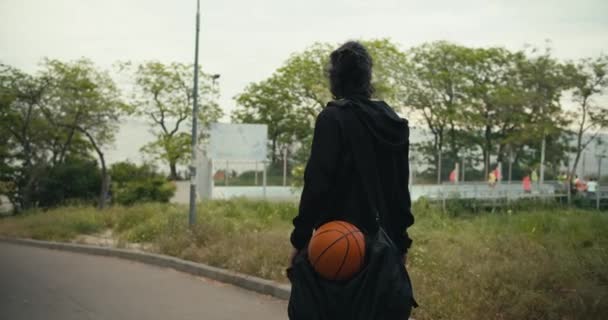 Hátsó Kilátás Egy Barna Férfi Fekete Dzsekiben Fekete Hátizsákkal Kosárlabdával — Stock videók