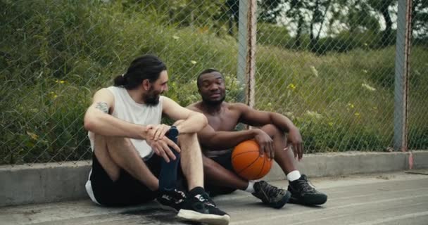 Dua Pria Sedang Duduk Lantai Lapangan Basket Dan Mengobrol Tentang — Stok Video