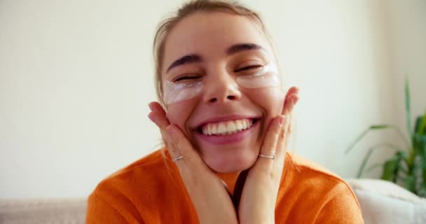 白い目の下の領域の世話のための化粧品をポーズオレンジセーターで美しいブロンドの女性の肖像画 パーソナルケア — ストック動画