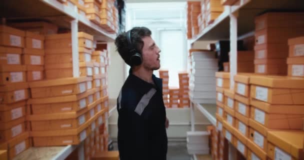 Man Blue Uniform Headphones Dances Shelves Yellow Boxes Warehouse — Stock Video