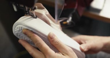 Yakın çekim: Tekstil fabrikasında özel bir ayakkabı yapma makinesinin taban ve üst dikişleri..