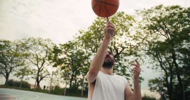 Medelålders Man Vit Shirt Snurrar Skickligt Orange Basket Pekfingret Idrottsplan — Stockvideo