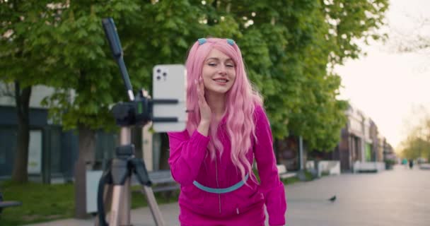 ピンクのきれいな女の子が三脚に立っている携帯電話で彼女の外観についてのビデオを撮影します 自分自身と一人の人格 自己肯定の宣言 — ストック動画