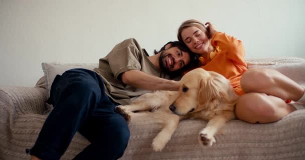 男と女の子はソファの上に横になり 彼らの明るい色の犬をストロークし 通信します ペットとの日常生活 — ストック動画