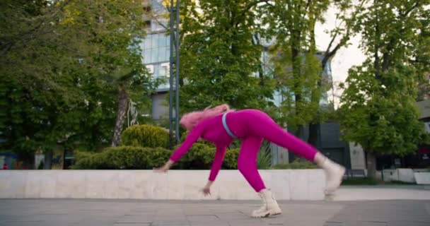 Счастливая Девушка Розовой Одежде Розовыми Волосами Делает Акробатический Трюк Улице — стоковое видео