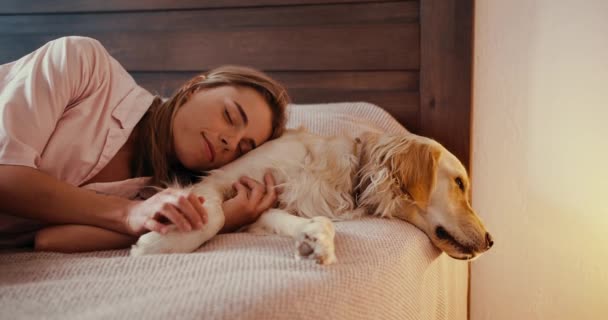 Beyaz Gecelikli Sarışın Bir Kız Açık Renkli Köpeğiyle Yatakta Yatıyor — Stok video