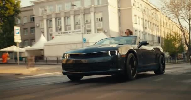 Ein Dunkelgraues Cabrio Fährt Die Straße Hinunter Ein Mädchen Das — Stockvideo