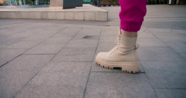 近くで撮影すると ピンクのパンツ姿の女の子と白いスニーカーが通りを歩いている フレームでは 女の子の歩行足 幸せな夏の散歩 — ストック動画