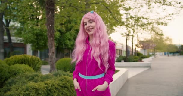 一个有着粉色头发和粉色衣服的非正式女孩的画像 她在街上摆姿势微笑 — 图库视频影像